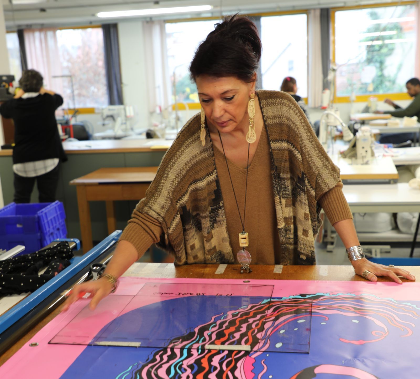 Meriem Toledano trace les patrons sur une bâche, pour la conception d'un sac cabas